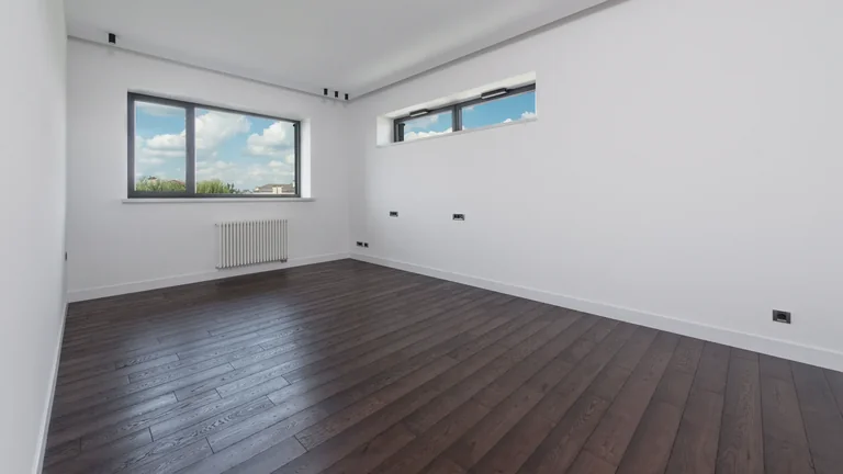 What is SPC vinyl flooring? Rigid core explained Empty modern room with dark wood-look plank flooring and white walls