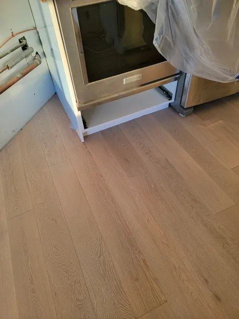 New engineered hardwood installed tight to existing kitchen cabinets after water damage, Toronto condo